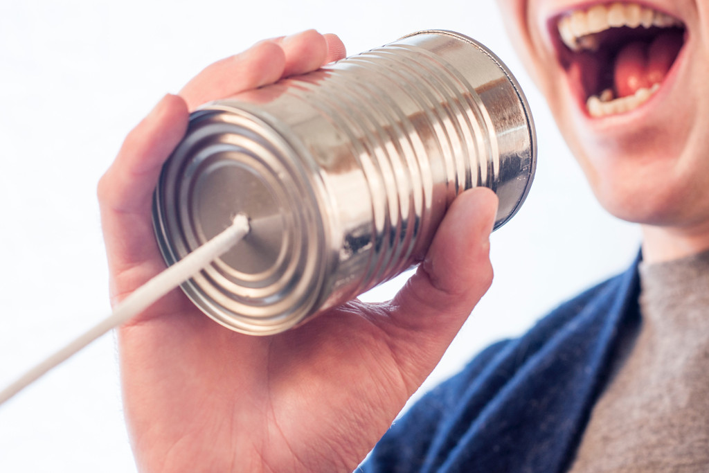 Man shouting into a metal can attached to a rope